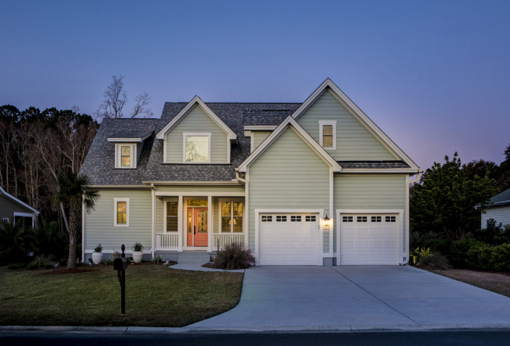 Two-story home with sage-green siding and coral front door at dusk, representing a mortgage-ready purchase